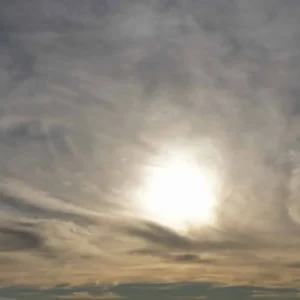 Grijze wolken met een waterige zon aan de horizon
