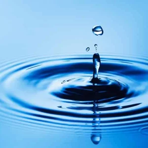 Waterdruppel in het midden van cirkelvormige rimpelingen op blauw water