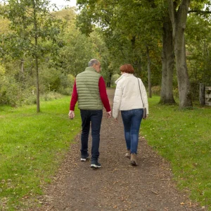 Coach en vrouw wandelen samen tijdens wandelcoaching in een groene omgeving